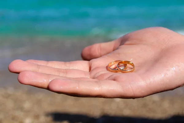 Två Vigselringar Handen Man Bakgrunden Stranden Och Havsvågen Smekmånad Efter — Stockfoto