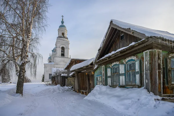 观看一座白色石头建成的乡村教堂 俄罗斯Nevyanskiy区Shurala 前面是一座木房子 有栅栏和一棵树 还有一条被雪覆盖的道路 冬季晴天 — 图库照片