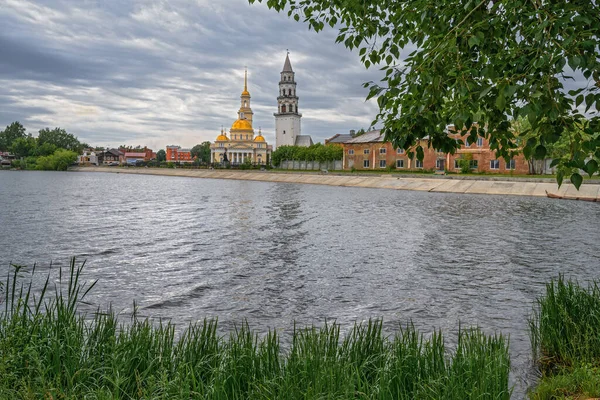 夏の日にネヴァヤンスキー池 遠くには正教会と有名な傾きの塔を持つネヴヤンスク ロシア の街の歴史的中心部があります 曇り青灰色の空 — ストック写真