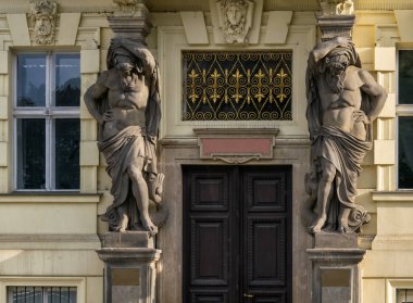 Atlantisli heykeller binanın girişinde. Güneşli bir yaz gününde Prag 'ın (Çek Cumhuriyeti) tarihi merkezinde yürümek. Binalardaki dekoratif mimari öğeler.