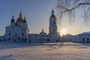 Soğuk bir kış sabahı antik altın kubbeli kiliselerin (Tobolsk, Rusya) manzarası. Kar beyazı duvarlar ve soluk mavi gökyüzü. Güneşin ışınları gökyüzünü ve karı ılık sarı tonlarda renklendirir.. 
