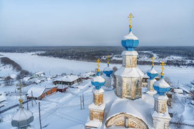 Kışın harika bir taşra kasabası olan Cherdyn 'in (Rusya) ve donmuş nehrin kuş bakışı manzarası. Eski beyaz taş kilisenin mavi kubbelerine yakın çekim. Her yer beyaz karla kaplı.