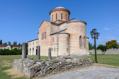 Yazın Pitsunda 'da (Abhazya) mavi gökyüzü ve yeşil çimlerle kaplı antik bir tapınak. Beyaz-turuncu çizgili tuğla ustalığı. Yakınlarda antik bir çan kulesinin kalıntıları var. 1000 yıllık bir kilise. 