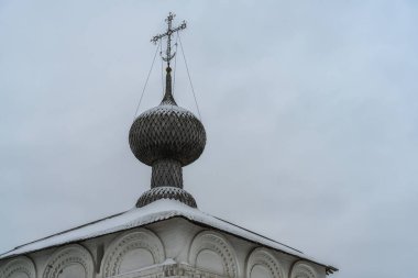 Solikamsk (Ural, Rusya) şehrindeki antik bir kilisenin haçına sahip, beyaz bir duvarda tuğla süslemelerle bembeyaz bir taç yaprak kubbesi. Yakın plan. Geleneksel eski Rus tarzı 