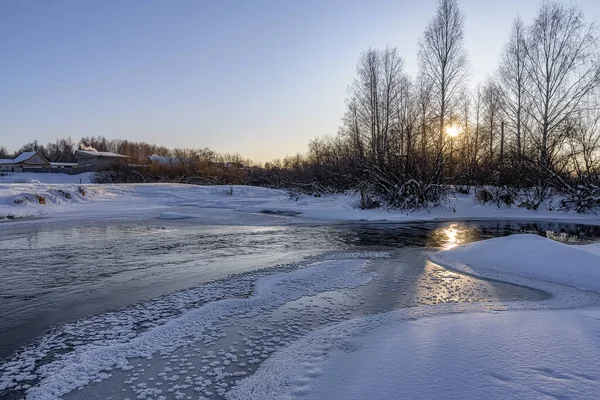 Beautiful textured ice in the form of stars on a freezing river, in which the sun is reflected. Photo taken on a frosty winter evening on the outskirts of a village in the Middle Urals (Russia)