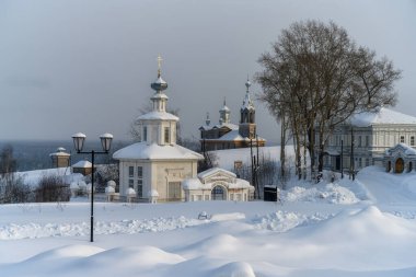 Soğuk bir kış gününde antik Cherdyn (Kuzey Urallar, Rusya) şehrinin manzarası. Derin karlı tarlaların üzerinde kubbeleri yükselen antik ahşap kiliseler. Dağ nehri vadisinin altında 