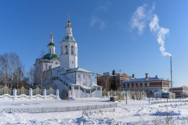 Soğuk bir kış gününde Tobolsk şehrindeki (Sibirya, Rusya) eski kilisenin manzarası. Kilisenin beyaz duvarları ve altın kubbeleri açık mavi gökyüzüne karşı harika görünüyor. Bacadan duman çıkıyor. 