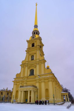Peter ve Paul Katedrali bulutlu bir bahar gününde Saint Petersburg 'da (Rusya). Kulesi, sütunları, kemerli pencereleri, saatleri ve portreleri olan görkemli sarı bir katedral. Bulutlu gökyüzü ve son kar 