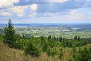 Yüksek bir dağdan manzaralı bir orman vadisine bir yaz günü. Görünürlük ufukta belirsizleşiyor. Kabartmalı bulutlu gökyüzü güneş tarafından aydınlatılıyor. Belaya Gora, Ural, Rusya 