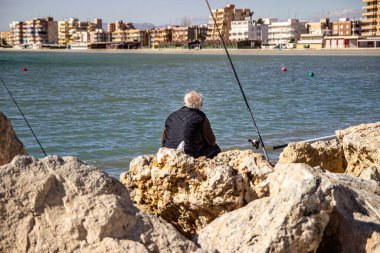 Emekli adam Akdeniz 'de balık tutuyor.