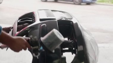 Atölyedeki araba boyacısı tamponları boyuyor.