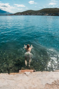 Yeşil mayo giyen genç atletik kadın güneşli bir günde Akdeniz 'de yüzer.