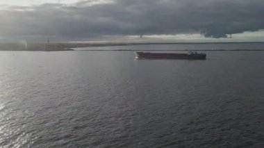 Kargo gemisi boyunca uçmak ve güneşe karşı iskele. Gemi limana gidiyor. 4K Hava Görüntüsü