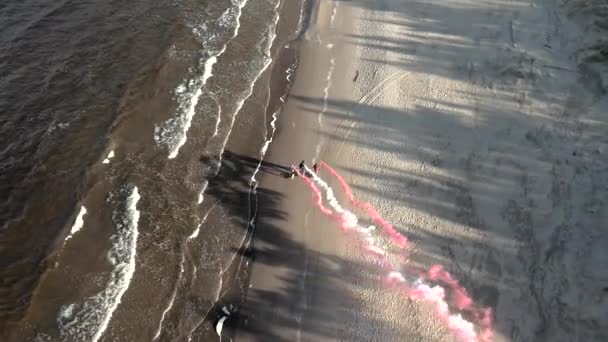 Eine Gruppe junger Leute auf Einrädern, Elektro-Skateboards mit rot-weißen Rauchgranaten am Meer. 4k Drohnen aus der Luft — Stockvideo