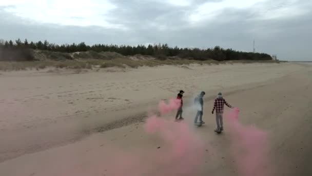 Group of young people riding onewheels, electric skateboards with red and white smoke grenades by the sea. 4K aerial drone view — Vídeos de Stock