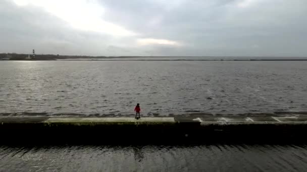 Young Asian man rides a onewheel, electric skateboards along a jetty along the sea. 4K Aerial drone view — 图库视频影像