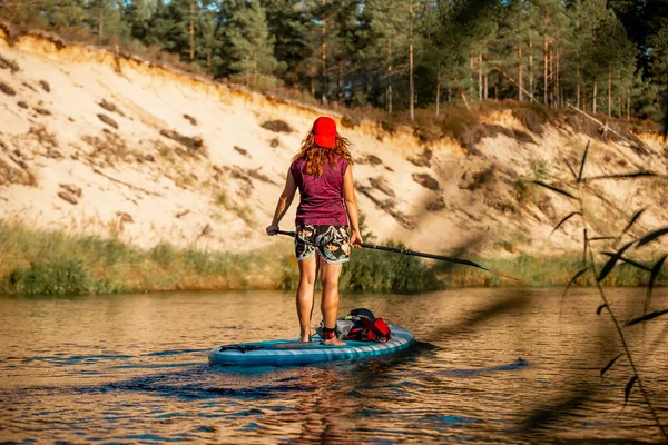 Kadınlar nehirde sörf yaparken ayağa kalkar. Arka görünüm
