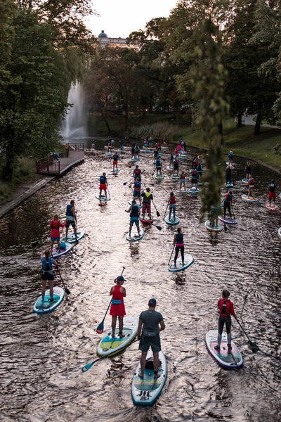 Bir grup insan, Letonya 'nın Riga şehrindeki bir kanalda SUP ile kürek çekiyor. Letonya 'da SUP turizmi