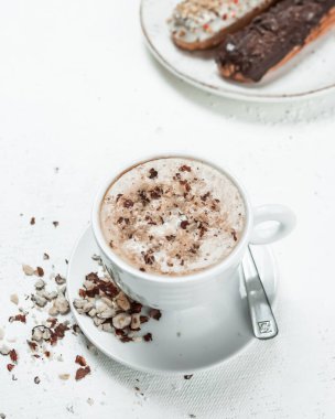 Beyaz bir masada fındıklı kapuçino ve köşede siyah çikolatalı geleneksel Fransız tatlı ekini.