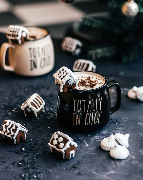 Coffee cappuccino mugs with gingerbread houses, cookies on a dark background