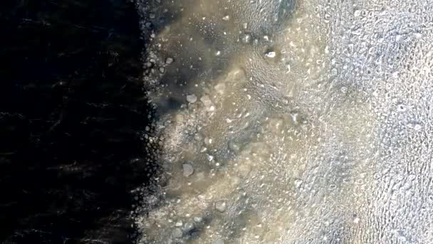 Eau sous glace sur mer gelée. Belle texture de glace et de neige lavée par les vagues. Vue depuis le drone — Video