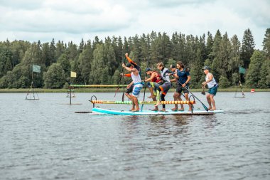 İnsanlar sıcak bir yaz gününde XI büyük SUP ile kürek çekiyorlar. Sportif insanlar tatilde eğleniyor.