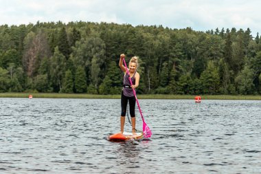 Genç kız kürek çekin ve gölde kürek çekin. SUP yarışması, yarış. muhteşem aktif açık hava eğlencesi.