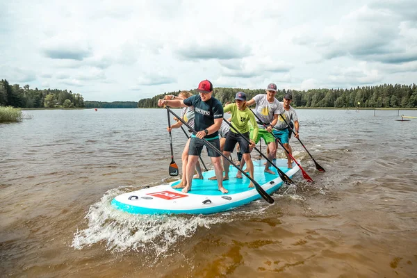 İnsanlar sıcak bir yaz gününde XI büyük SUP ile kürek çekiyorlar. Sportif insanlar tatilde eğleniyor.
