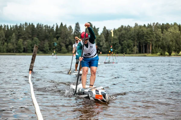 SUP 'u olan mutlu insanlar gölde ayağa kalkın. SUP yarışması, yarış. muhteşem aktif açık hava eğlencesi.
