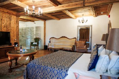 Ilık aydınlatma odaları aydınlatır. Kereste kirişleri, antika kanepeler, kıvrımlı koltuklar, desenli yorganlar, avizeler ve görünür bir cam bölme banyosu ile..