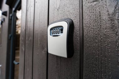 Gündüz vakti duvarlara monte edilmiş bir anahtar kasasını dikey, koyu renkli tahta tahtaların üzerine koy. Yumuşak bulutlu ışık su damlacıklarını, sığ derinlik izolasyonlarını gösterir.