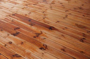 Paralel ahşap döşemeler yeni yağan yağmurdan kararmış düğümler ve çizgiler gösteriyor. Sığ açı bileşimi yönsel ışık yansımaları ile doğrusal detayı vurgular.