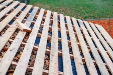 Eğik ahşap yarasalar siyah bir iç çamaşırını gerer, sonbahar yaprakları kirişlerin arasında oturur, tek bir kesme bloğu tepesinde durur, doğal gün ışığı açık havada sonbahar işi olduğunu öne sürer..