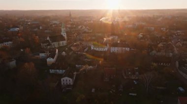 Güneş doğarken havadan bakıldığında yeşil kulesi, kiremitli çatıları, dar sokakları ve muhtemelen Orta Avrupa 'da sabahın erken saatlerinde çıkan baca dumanı olan beyaz bir kilise görülüyor.