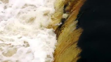 Nehrin yukarısında, aşağı doğru, karanlık havuza doğru hızla akıyor. Sola beyaz köpük, sağa altın şelale. Gün ışığı, sıkı çerçeve, gevrek hareket detayı.