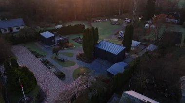 Koyu modüler binalar, tuğla sürücüler, Evergreen 'ler, gölet, oyun alanı ve gün doğumunda don ve uzun gölgelerle birlikte uzak su kulesi olan bir kırsal yerleşke üzerinde havadan tava..