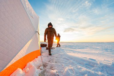İki balıkçı gün doğumunda donmuş kar üzerinde çalışır, uzun gölgeler uzar. Biri dikişli elmasa doğru yürüyor, diğeri kızağın yanında duruyor, nefesi soğuktan anlaşılıyor..