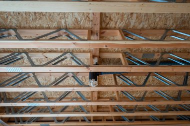 Kabartma ahşap kirişler, çelik ağlar, OSB, ve mavi kanallı merkezi bir kanal, hatta gün ışığında, kabataslak içinde, modüler hassasiyet gösteren.