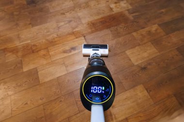 Kablosuz ıslak kuru vakum kapalı alanda ahşap üzerinde çalışır, beyaz fırça başı ve akıllı kontroller görünür,% 100 pil gösterilir, kuru çizgiler temizlenir ve nemlenir..