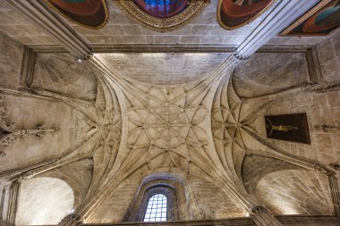 Tonozlu tavan ve Seville Katedrali 'nin içindeki yıldız tırtıklı kasa. Gotik sütunlar sivri kemerlere yükseliyor, uzun ızgara bir pencere ve resimler kutsal bir iç mekan oluşturuyor..