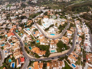 Marbella 'nın havadan görünüşü, Costa del Sol. Terracotta çatı villaları. Havuz kenarları kıvrımlı yollar. Beyaz modern bir kompleks duvarlı bir yaylada, palmiyelerde ve golf sahalarının ötesinde..