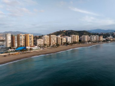 Malaga 'daki Malagueta Sahili' nin hava sahili kum, turkuaz su, palmiyeler, chiringuitos, yüksek kuleler ve Gibralfaro tepesini öğleden sonra aydınlığında gösteriyor..