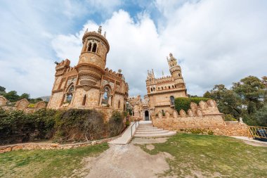 Benalmadena 'daki Castillo de Colomare, Malaga süslü taretler, neo Mudejar kemerleri ve yarılmış duvarlarla ayakta duruyor. Yer manzarası kuleleri, merdivenleri ve ziyaretçileri gösteriyor..