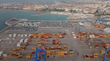 İspanya 'nın Akdeniz konteynır limanına bakan vinçler, konteynırlar, park edilmiş araçlar, rıhtımlar, tanklar ve sahil kenarındaki yelkenliler..