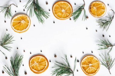 Noel arkaplanı kurumuş portakallar, siyah biberler ve beyaz bir arka planda çam dalları. Üst görünüm, düz görünüm, kopyalama alanı