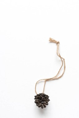 Beyaz arka planda çam kozalağından yapılmış ev yapımı Noel ağacı oyuncağı. Kopya alanı olan kutlama kartı