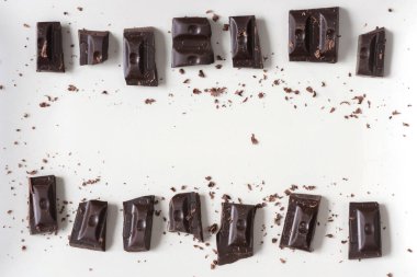 Açık arkaplanda siyah çikolata parçaları. Üst görünüm, düz görünüm, kopyalama alanı.