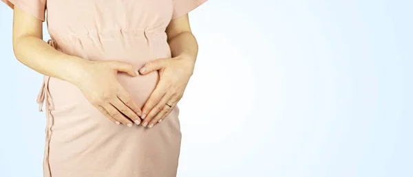 Mavi arka planda hamile bir kadın. Yatay fotoğrafçılık, izole kişi.