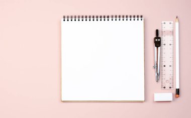 Pembe arka planda, pusula, cetvel, kalem, silgi gibi şeyleri yazmak ve çizmek için bir yay üzerine kare defter. Fotokopi alanı ile pembe arkaplan. İş ve okul için arka plan. Düz yatıyordu. Okula dönelim. Okul öğrenme konsepti. Boşluğu kopyala.