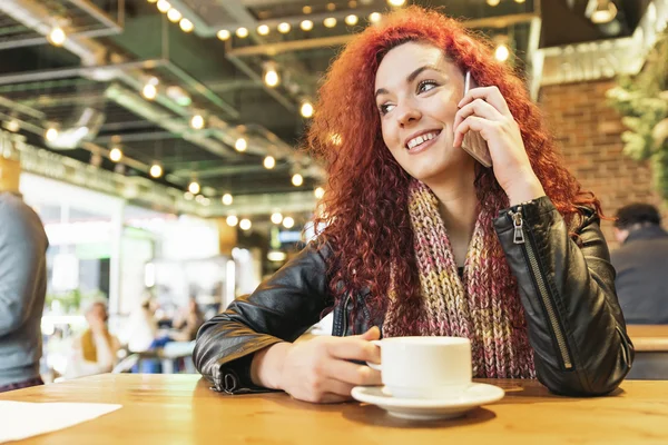 Fiatal nő beszél a telefonon, a kávézóban. — Stock Fotó